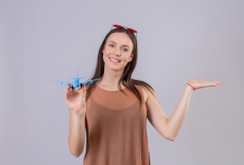Smiling woman holding a blue airplane model, symbolizing easy travel with Smileie clear aligners.