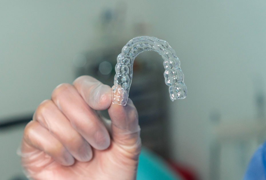 Clear dental aligner held by a professional for clear aligner treatment in Palm Harbor, FL.