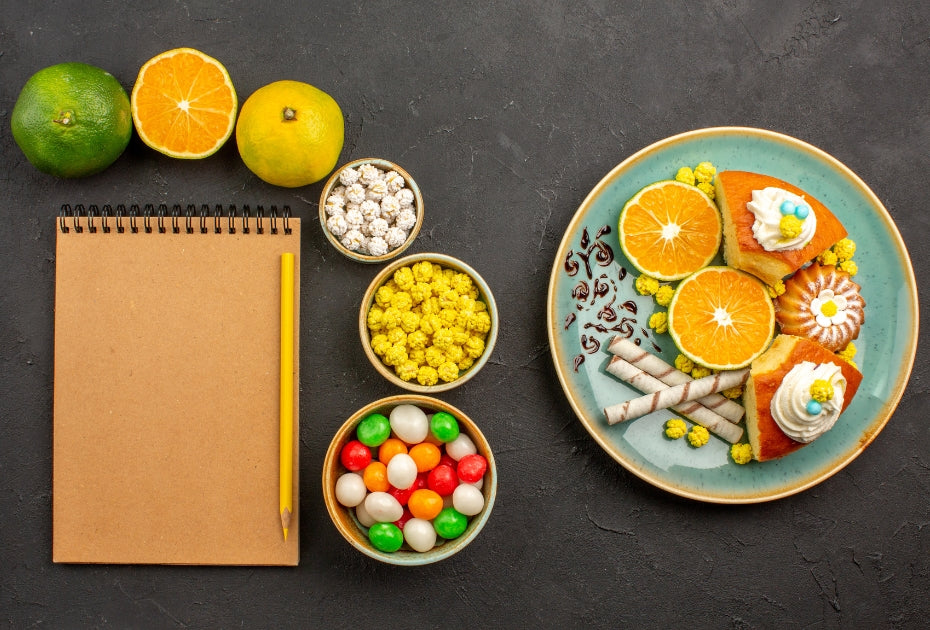 Orthodontic-friendly snacks with citrus slices, small sweets, and notepad on dark background