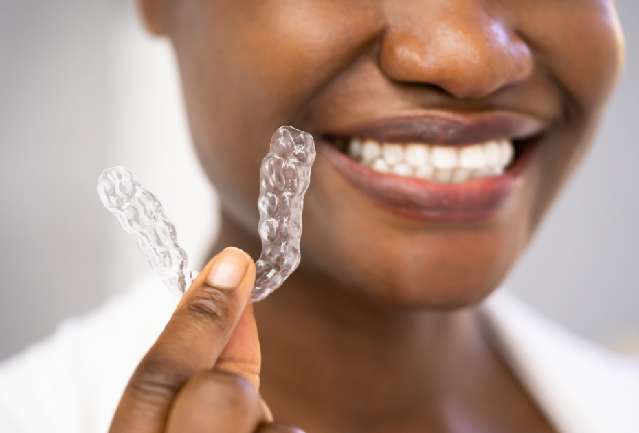 Woman smiling and holding clear aligners for teeth straightening