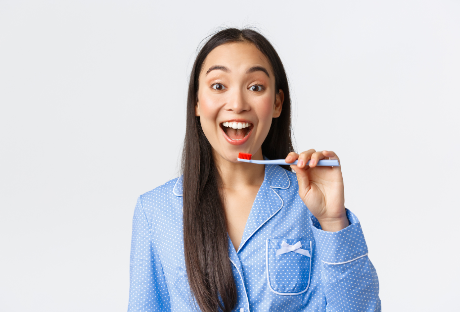 Smiling woman holding a toothbrush, ready to brush her teeth, on a clean white background.