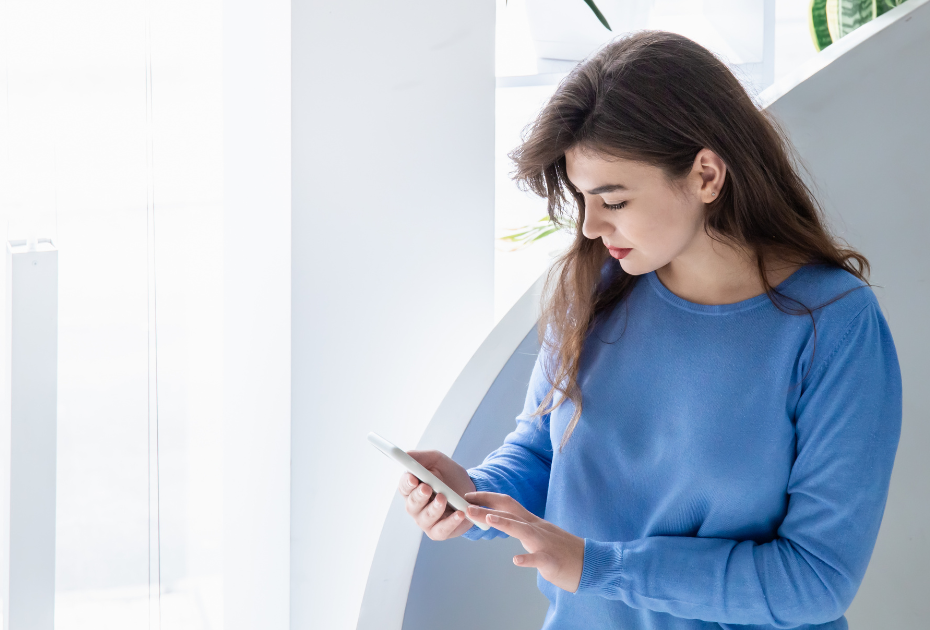 Woman using smartphone to submit smile progress photos for online aligner monitoring during at-home clear aligner treatment.
