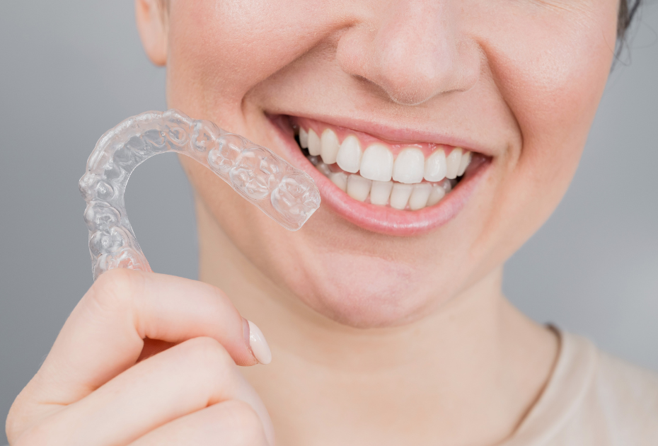 Woman holding clear aligners in her hand before starting teeth straightening treatment.