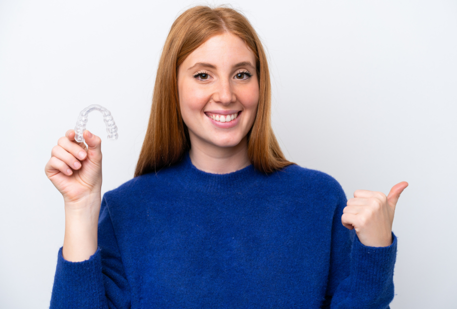Smiling adult woman holding a clear aligner tray, representing invisible braces for adults and discreet orthodontic treatment