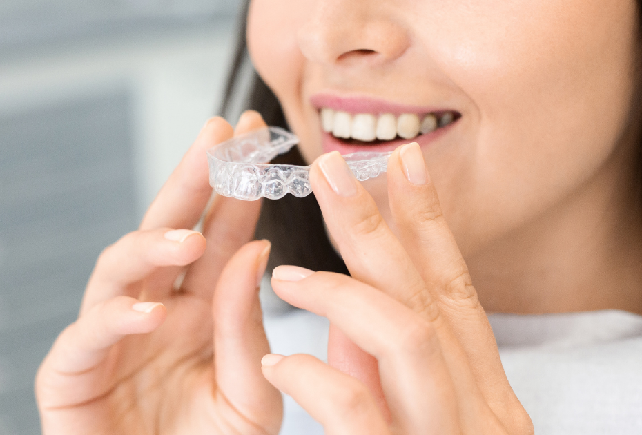 Person holding clear aligner tray near smile before wearing it