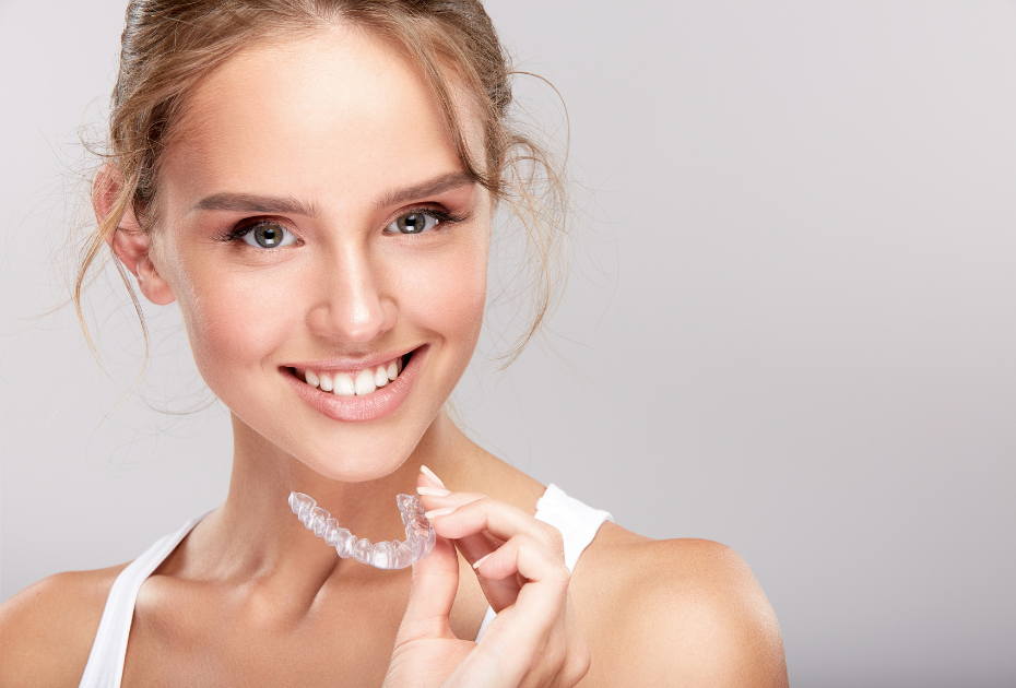 Young woman holding invisible teeth aligners during aligner adjustment phase