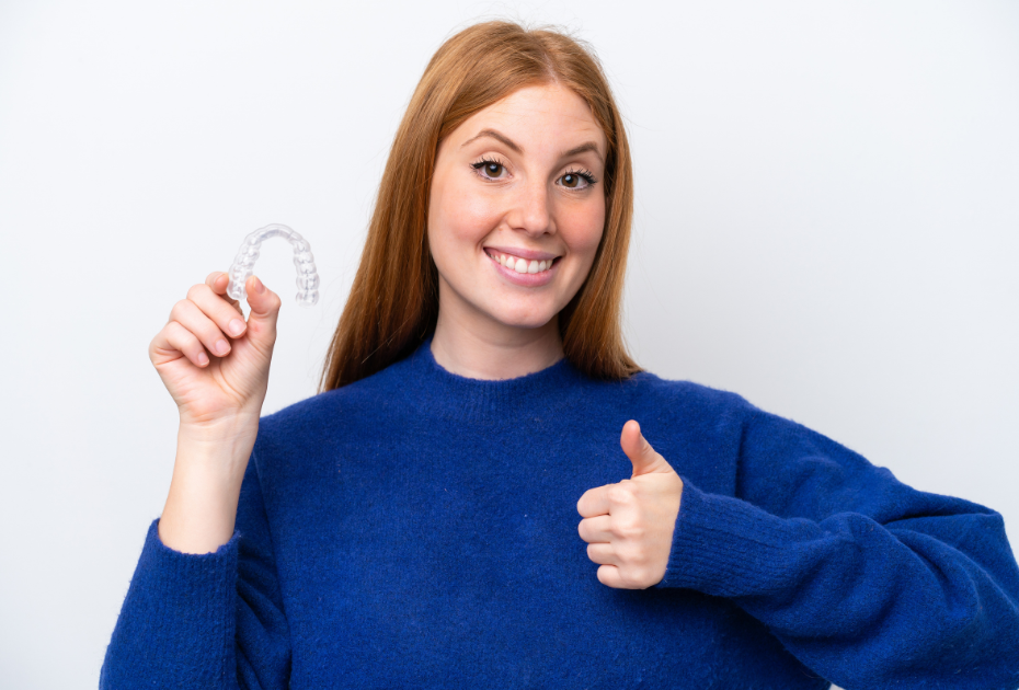 Woman holding clear aligner and smiling, representing how to choose the right clear aligners plan based on smile goals