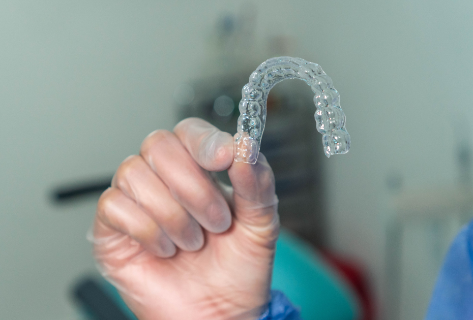 Clear aligners eligibility USA – dental professional holding invisible aligner tray.