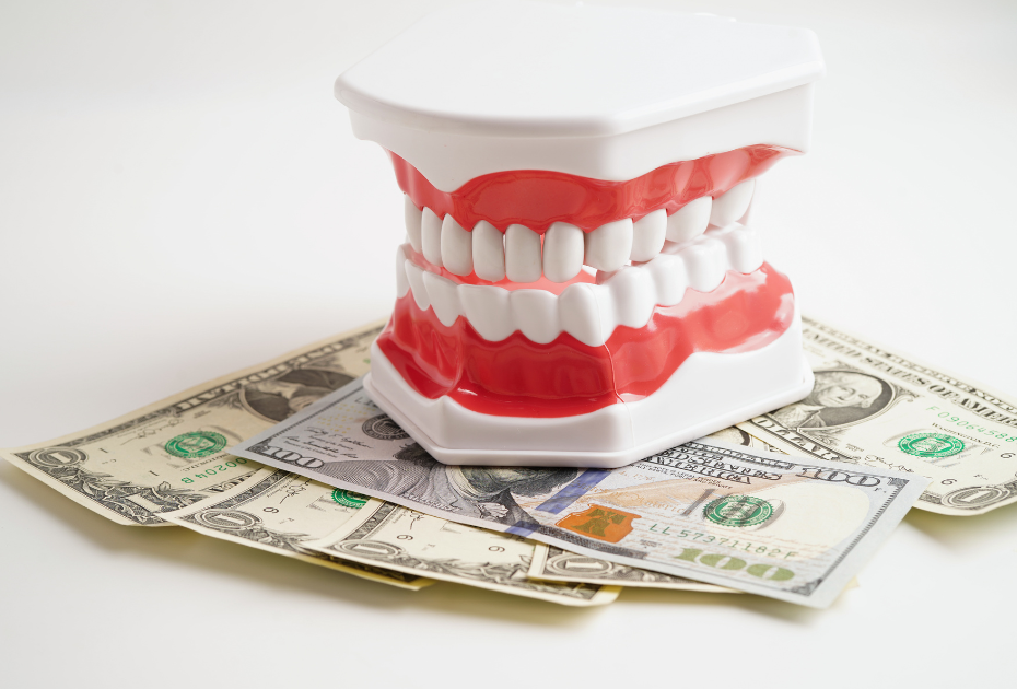 Dental model with white teeth resting on U.S. dollar bills, symbolizing the cost of dental treatment or dental care expenses.