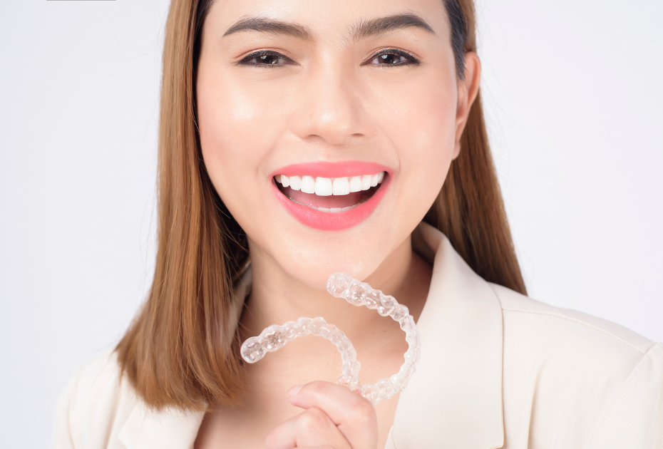 Woman holding pair of clear aligners for bite correction